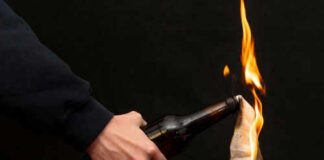 Person holding molotov cocktail with flame burning cloth