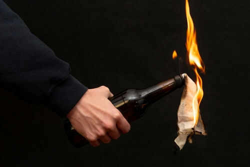 Person holding molotov cocktail with flame burning cloth