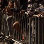 People leaning on barriers at an outdoor event
