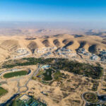 Iranian Missiles Breach Israel’s Iron Dome Aerial view of a desert landscape with a residential area and green spaces