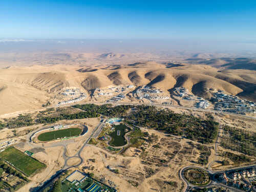 Aerial view of a desert landscape with a residential area and green spaces