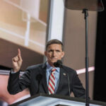 A speaker gesturing while addressing an audience at a conference