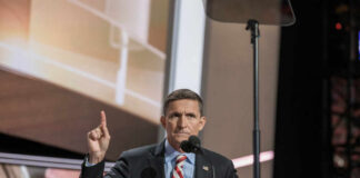 A speaker gesturing while addressing an audience at a conference