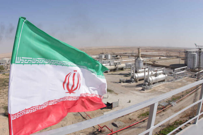 Iranian flag waving in front of an oil processing facility