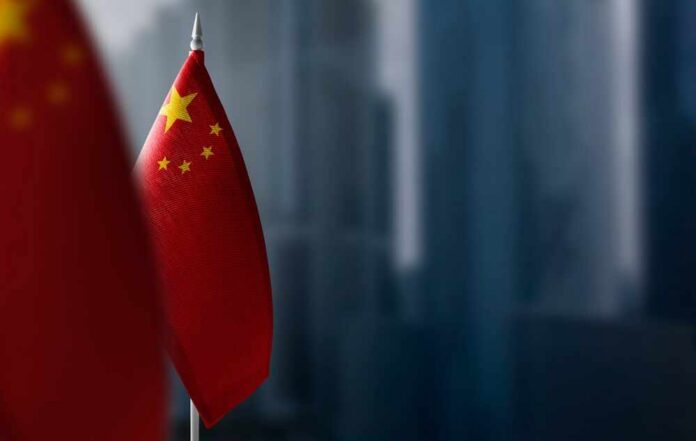 Close-up of the Chinese flag on a flagpole with a blurred urban background