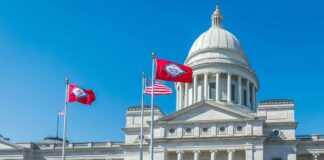 State capitol building with flags in front against a clear blue sky