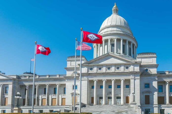 State capitol building with flags in front against a clear blue sky
