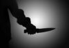Silhouette of a hand holding a knife against a light background