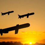 Trump’s Navy Faces DIRE Missile Shortage Silhouettes of missiles flying against a sunset backdrop