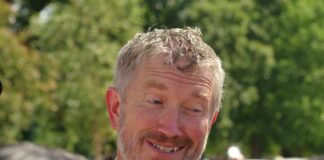 A smiling man in a suit engaging in conversation outdoors
