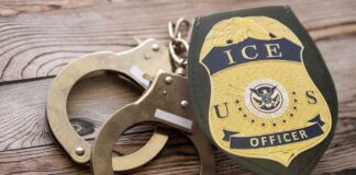 Handcuffs and a police badge on a wooden surface