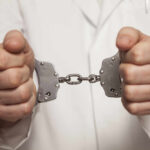 Healthcare Horror: 15-Year Fraud Scheme Revealed A person in a white coat holding handcuffs tightly