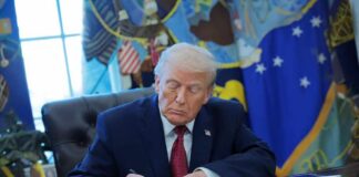 Donald Trump signing documents in the Oval Office