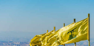 Multiple yellow flags waving in the wind against a clear sky