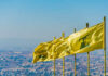 Multiple yellow flags waving in the wind against a clear sky