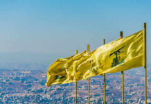 Multiple yellow flags waving in the wind against a clear sky