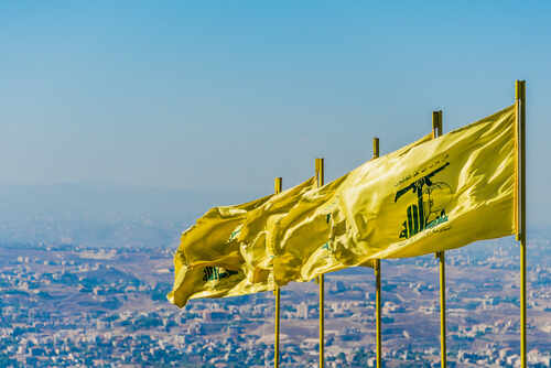 Multiple yellow flags waving in the wind against a clear sky