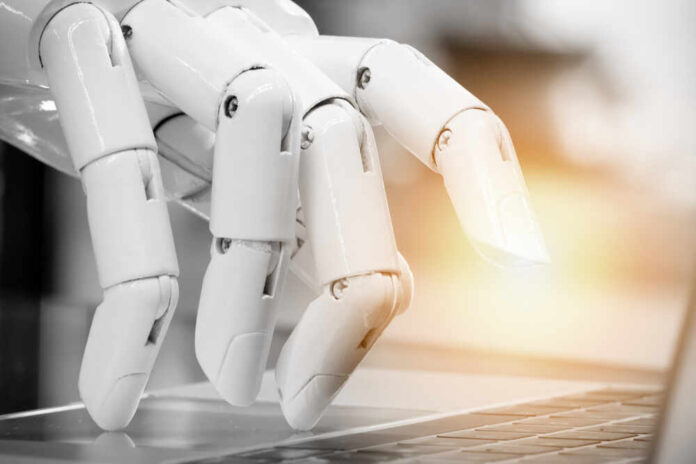 A robotic hand poised above a laptop keyboard