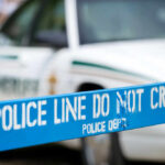 Police line marked with caution tape in front of a police vehicle