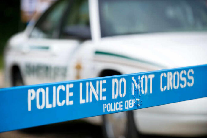 Police line marked with caution tape in front of a police vehicle