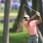 Golfer swinging club on green golf course
