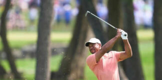 Golfer swinging club on green golf course