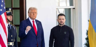 Two men standing outdoors near flags and doorway