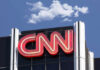 CNN building sign against blue sky with clouds.