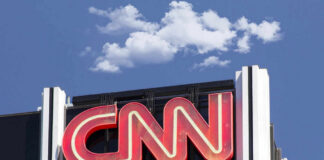 CNN building sign against blue sky with clouds.