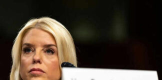 Woman seated next to nameplate at event