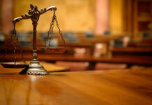 A close-up of a decorative scales of justice on a wooden table in a courtroom
