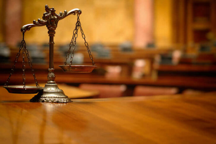 A close-up of a decorative scales of justice on a wooden table in a courtroom