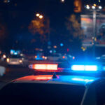 Police car with flashing blue and red lights in a city at night