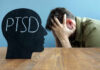 Silhouette of a head with 'PTSD' written on it, with a person in distress in the background