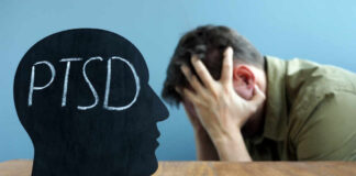 Silhouette of a head with 'PTSD' written on it, with a person in distress in the background
