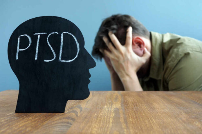 Silhouette of a head with 'PTSD' written on it, with a person in distress in the background