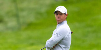 A golfer in sportswear looking intently on the golf course