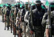 Uniformed individuals in a military parade holding weapons