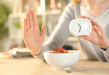 Person holding an alarm clock with a bowl of cereal in front