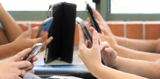 Students' hands holding smartphones in a classroom