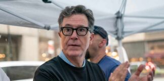 Person clapping at a protest wearing a Writers Guild of America t-shirt