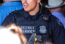 A Secret Service officer in tactical gear with a radio and firearm