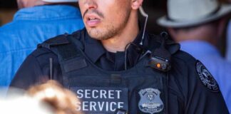 A Secret Service officer in tactical gear with a radio and firearm