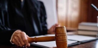 A judge's hand holding a gavel in a courtroom setting