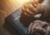 Two hands clasped in prayer over a Holy Bible