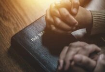 Eviction Chaos: Islamabad’s Christians Under Siege Two hands clasped in prayer over a Holy Bible