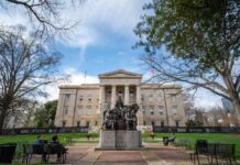 Historic building with a statue in front and people sitting on benches