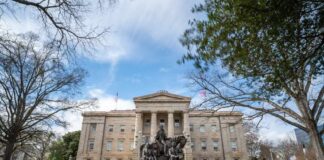 Historic building with a statue in front and people sitting on benches