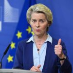 A female leader giving a thumbs up during a press conference