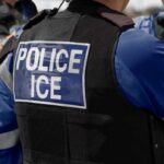 Close-up of a police officer's vest with 'POLICE ICE' insignia